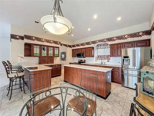 a kitchen with stainless steel appliances granite countertop a stove a sink dishwasher a dining table and chairs with wooden floor