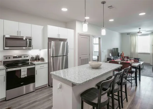a kitchen with granite countertop a table chairs microwave and refrigerator