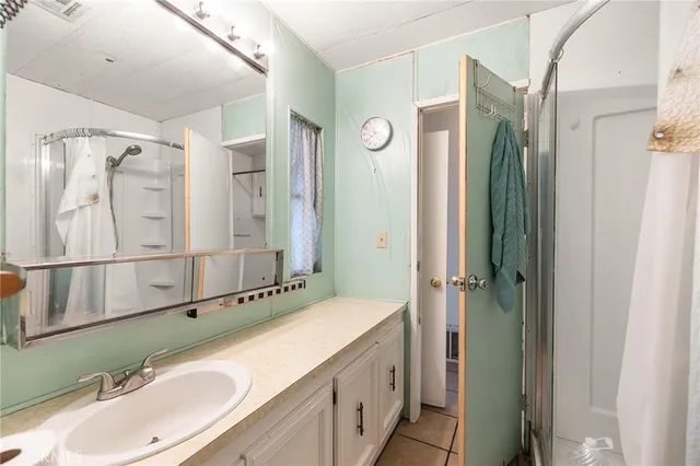 a bathroom with a granite countertop double vanity sink mirror and shower