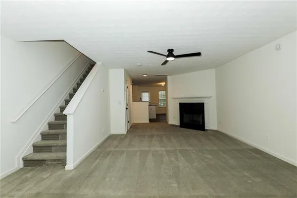 a view of an empty room with stairs and a fireplace