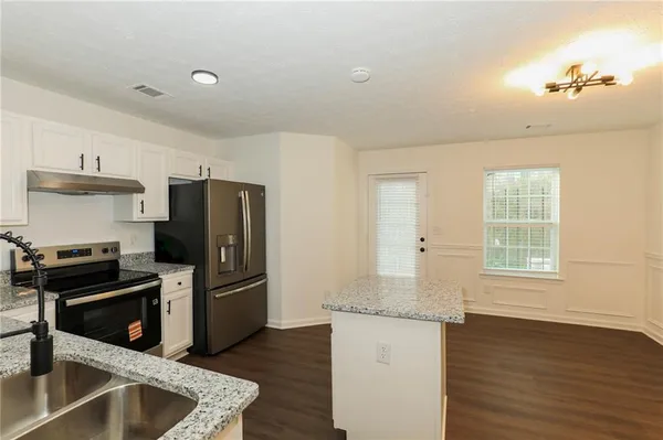 a kitchen with granite countertop a refrigerator stove and sink