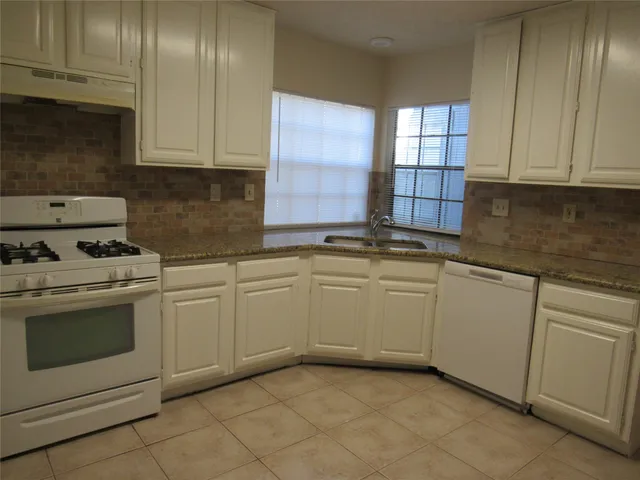 a kitchen with granite countertop white cabinets and white appliances