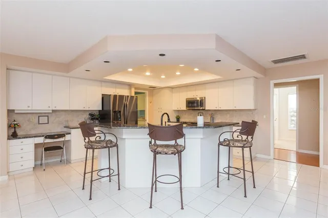 a kitchen with stainless steel appliances kitchen island granite countertop a table and chairs in it