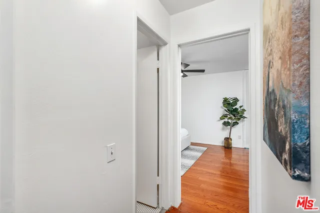 a view of a hallway with wooden floor and a bathroom