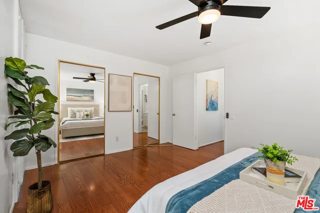 a bedroom with a bed potted plant with the wooden floor