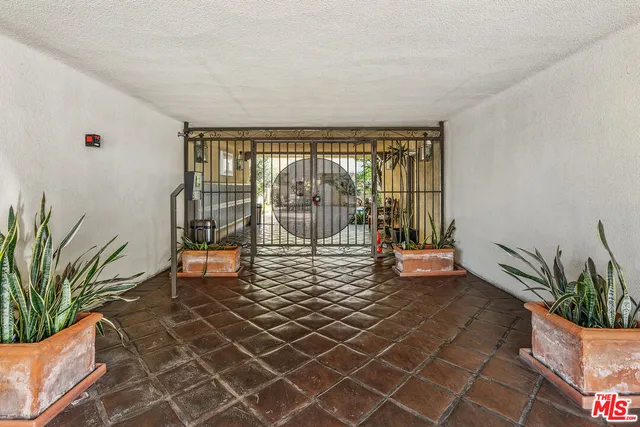 a living room with a large window and potted plants