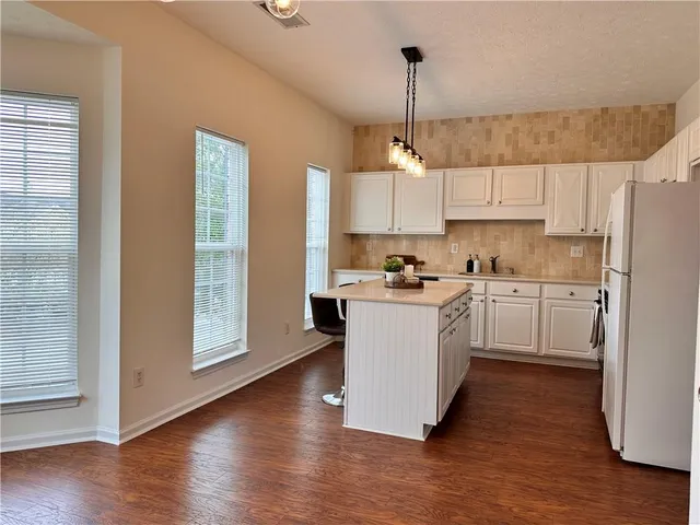 a kitchen with white cabinets and window