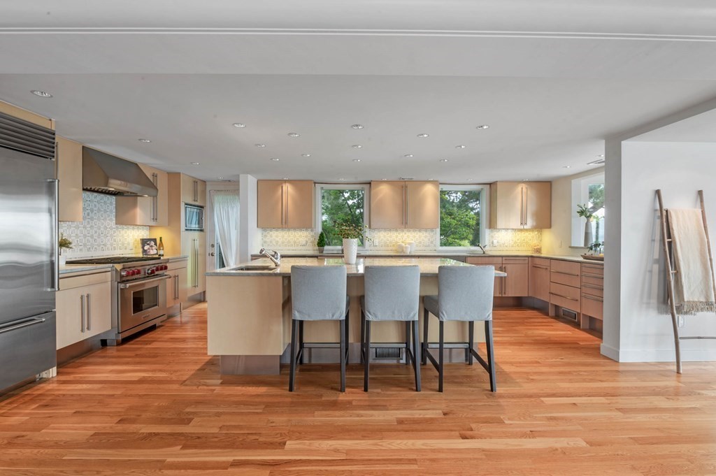 13 Goldthwait Road Marblehead, MA 01945 - Photo 8 of 40 a kitchen with stainless steel appliances kitchen island granite countertop a stove top oven a sink dishwasher a dining table and chairs with wooden floor