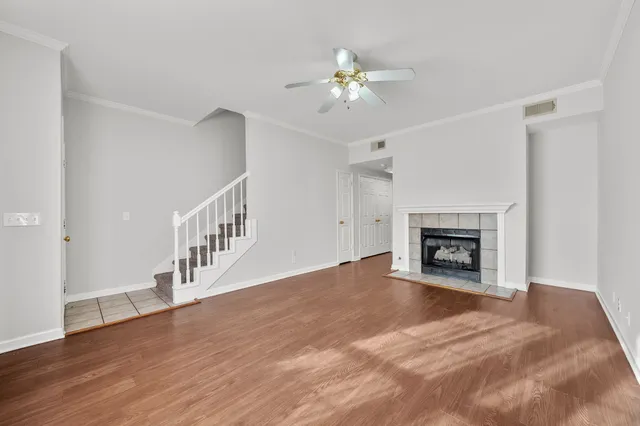 a view of an empty room with wooden floor and fireplace