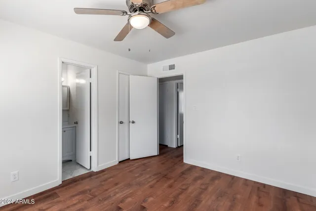 an empty room with wooden floor ceiling fan and windows