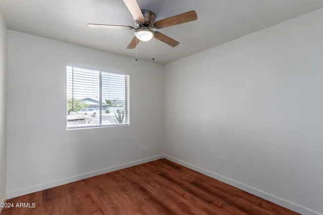an empty room with wooden floor fan and windows