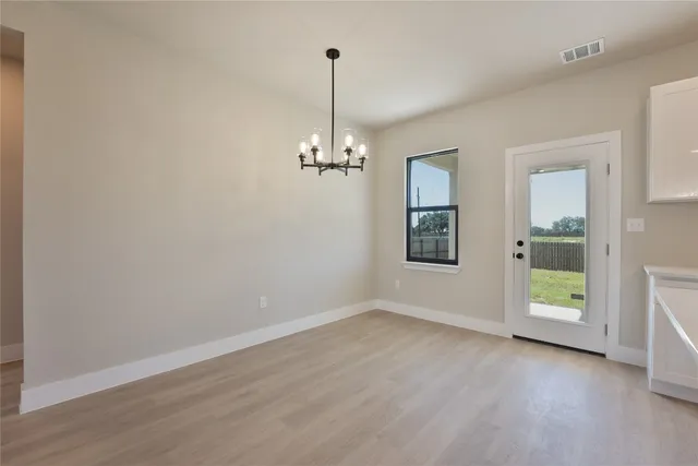 a view of a room with wooden floor chandeliers and window