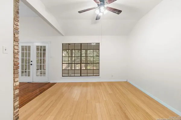 a view of an empty room with wooden floor and a window