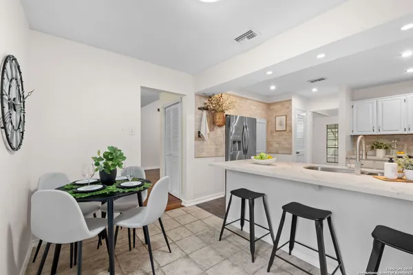 a kitchen with stainless steel appliances a dining table chairs and a refrigerator