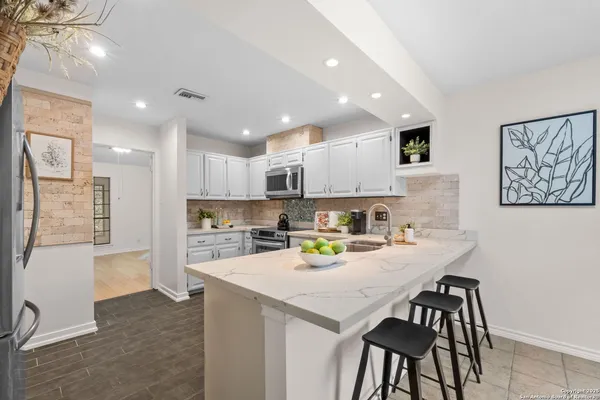 a kitchen with a sink a stove a refrigerator and white cabinets with wooden floor