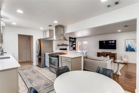 a living room with stainless steel appliances furniture a flat screen tv and a view of kitchen