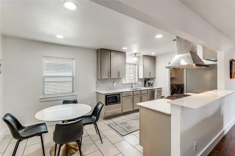 a kitchen with stainless steel appliances kitchen island a table chairs in it and wooden floors