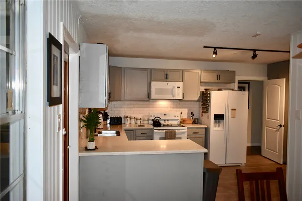 a kitchen with stainless steel appliances a refrigerator a sink a stove and white cabinets