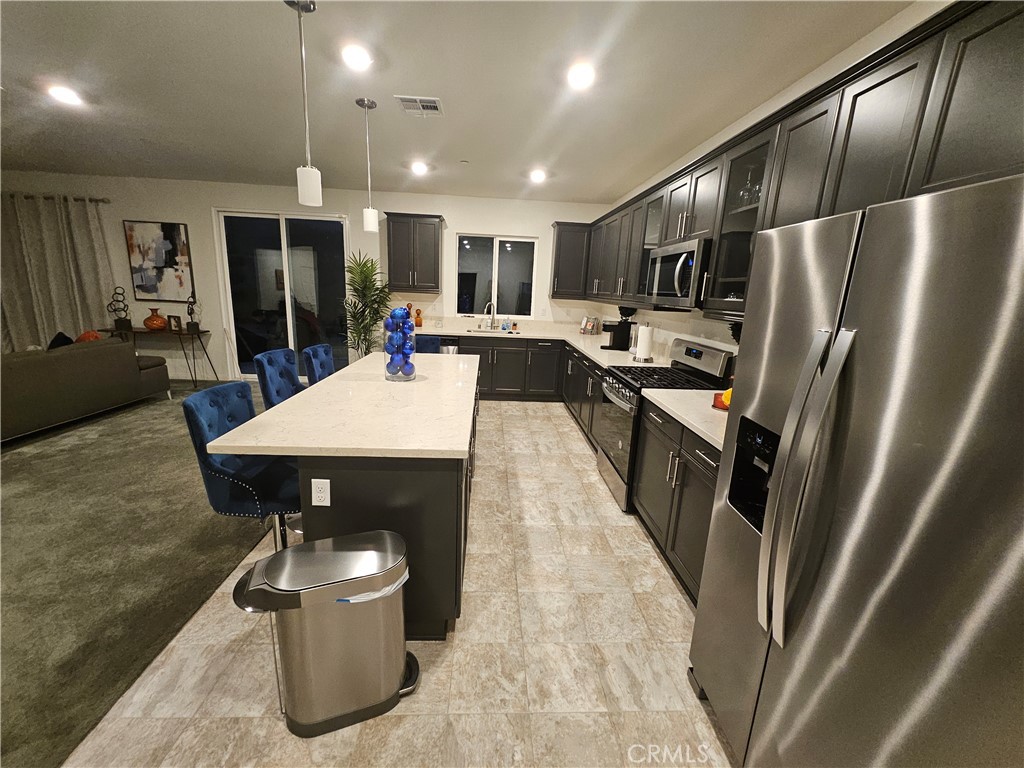 7900 Raincross Court Riverside, CA 92507 - Photo 4 of 21 a kitchen with stainless steel appliances a refrigerator a sink a stove a dining table and chairs