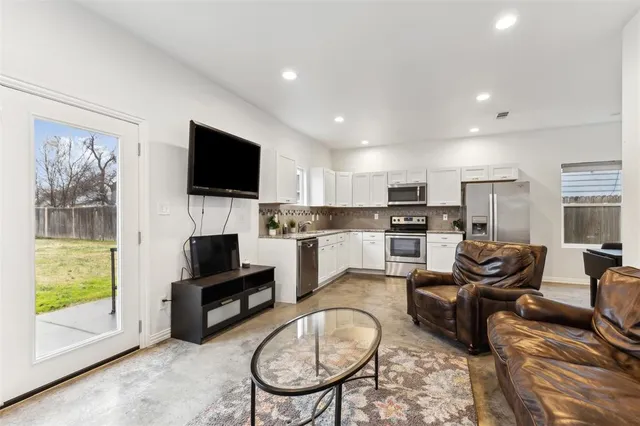a living room with stainless steel appliances furniture and a view of kitchen