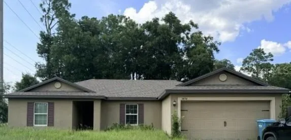 a view of a house with a yard plants and large tree