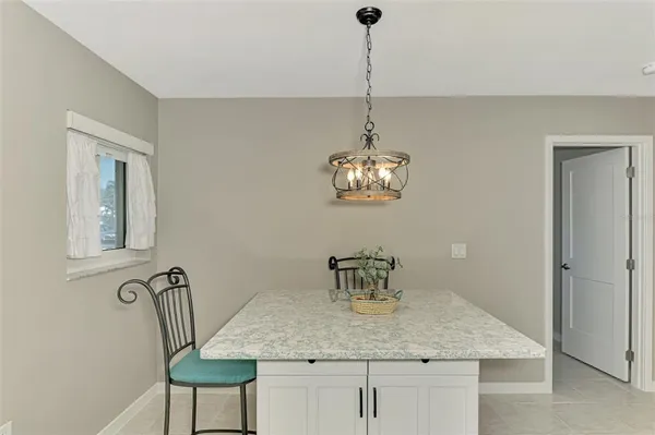 a kitchen with stainless steel appliances granite countertop a sink a refrigerator and chairs