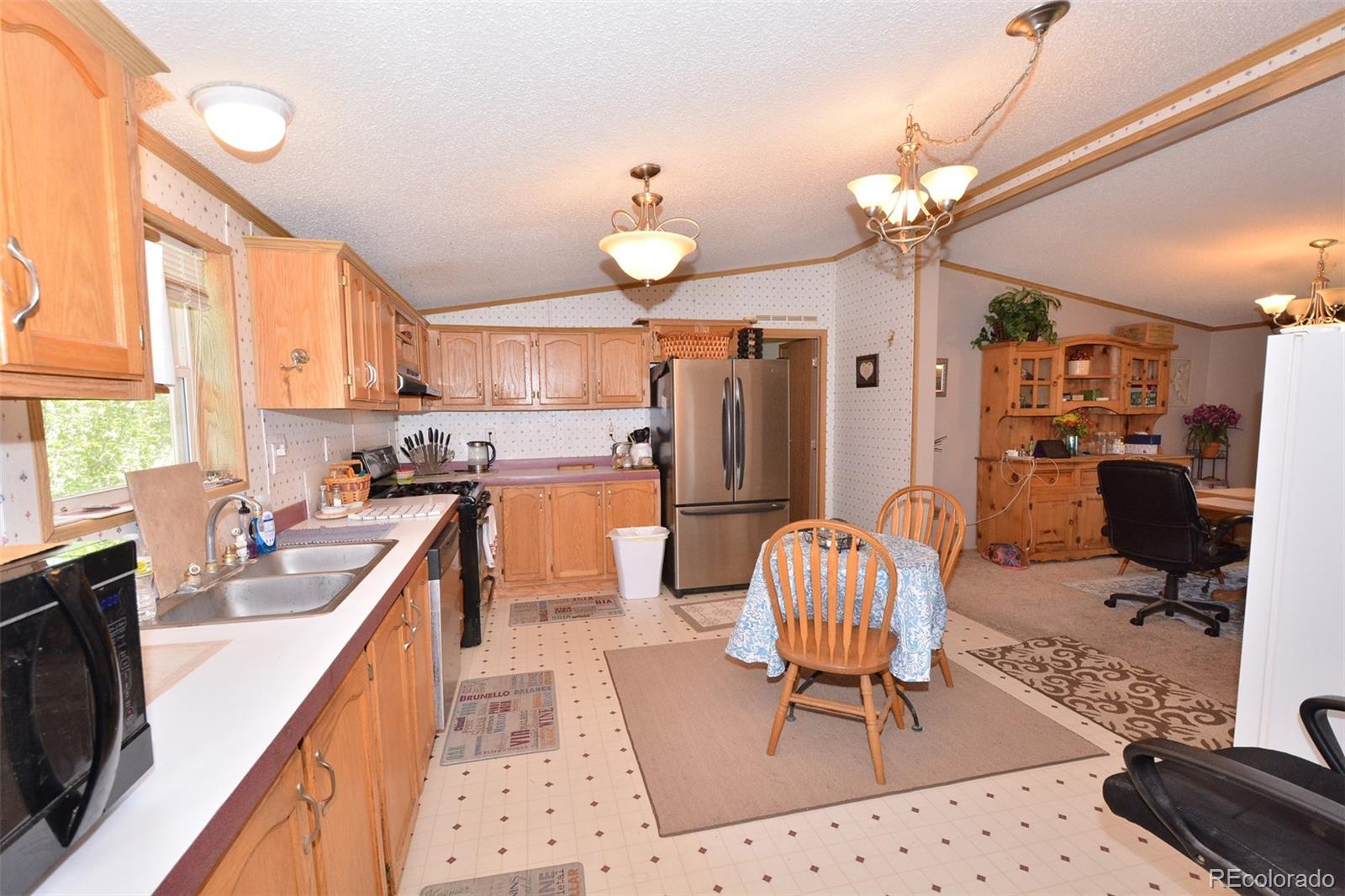30640 Aldred Road Pueblo, CO 81006 - Photo 20 of 34 a kitchen with stainless steel appliances kitchen island granite countertop a refrigerator oven a sink a dining table and chairs with the large window