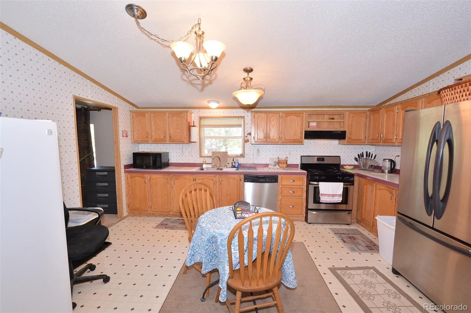 30640 Aldred Road Pueblo, CO 81006 - Photo 21 of 34 a kitchen with stainless steel appliances kitchen island granite countertop a refrigerator a stove a sink dishwasher a dining table and chairs with wooden floor