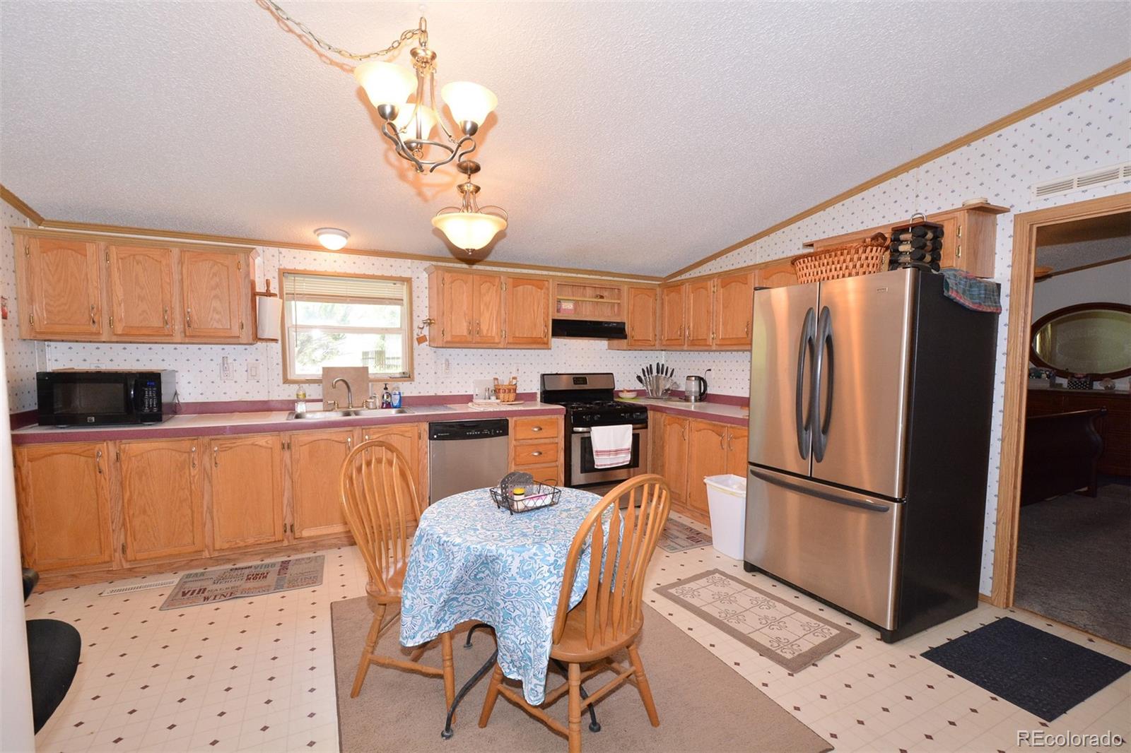 30640 Aldred Road Pueblo, CO 81006 - Photo 23 of 34 a kitchen with stainless steel appliances granite countertop a refrigerator a stove a sink dishwasher and a dining table with wooden floor