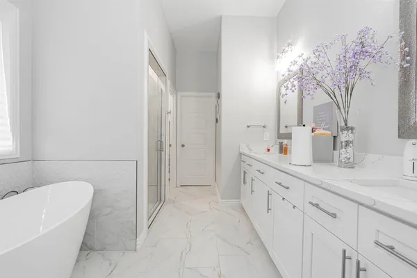a spacious bathroom with a double vanity sink a mirror and a bathtub