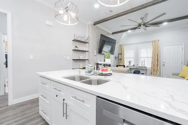 a white kitchen with a sink and dishwasher with wooden floor