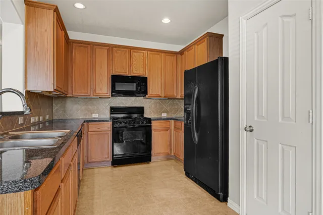 a kitchen with stainless steel appliances granite countertop a refrigerator stove and sink