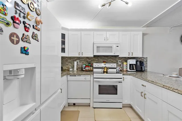 a kitchen with granite countertop white cabinets and white appliances