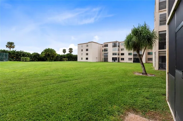 a view of a house with a big yard and palm trees
