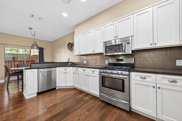 a kitchen with stainless steel appliances a refrigerator and wooden floor