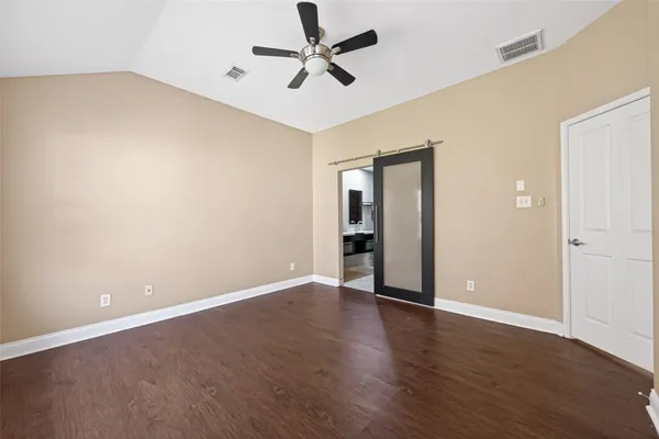 an empty room with wooden floor fan and windows
