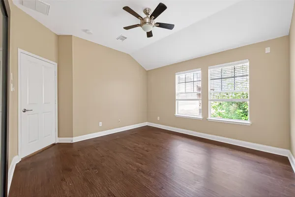 an empty room with wooden floor and a ceiling fan