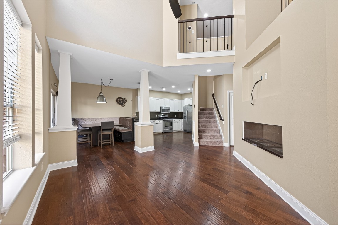 65 Scarlet Woods Court Spring, TX 77380 - Photo 36 of 36 This spacious home features an open floor plan with high ceilings, hardwood floors, and abundant natural light. The kitchen is modern with stainless steel appliances, adjacent to a cozy dining area. A staircase leads to an upper level with a railing overlooking the main floor.