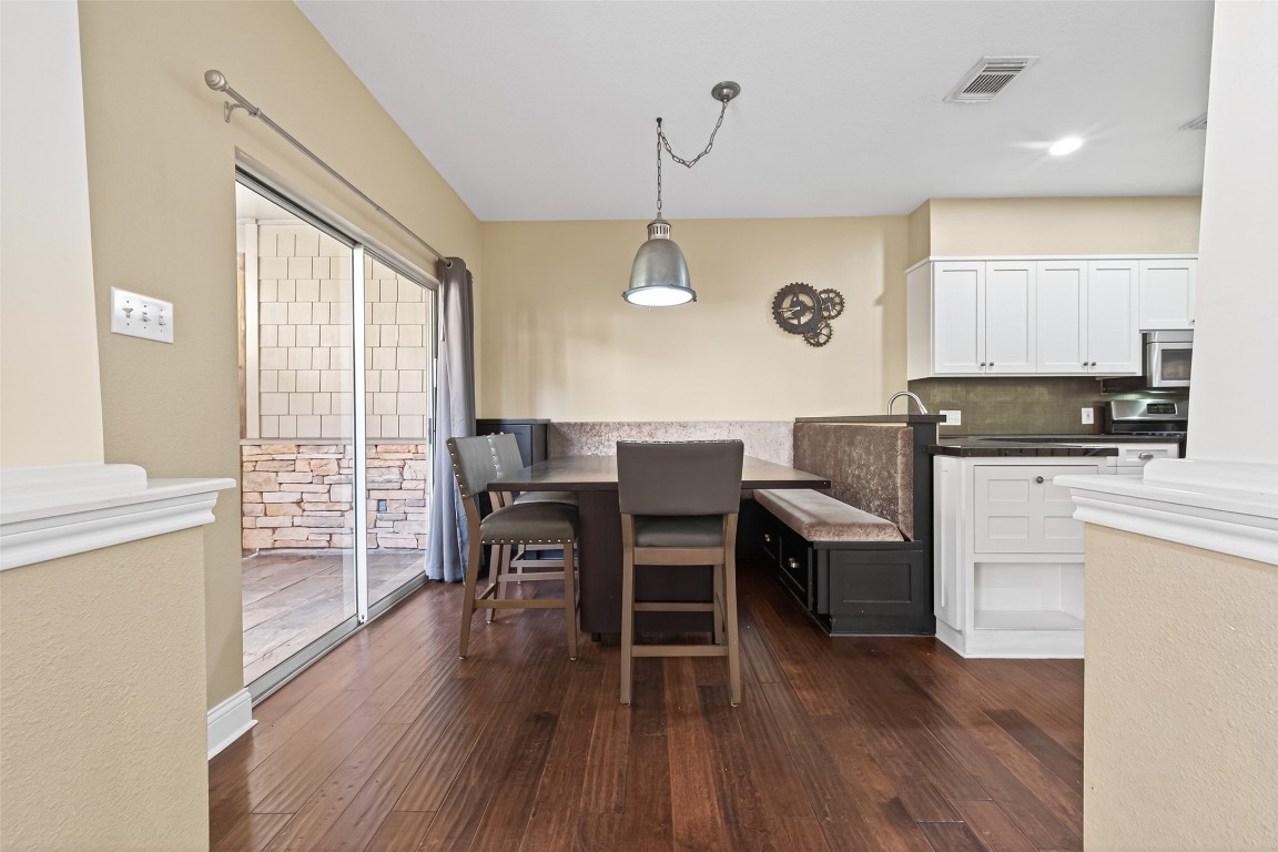 65 Scarlet Woods Court Spring, TX 77380 - Photo 6 of 36 This cozy dining area features a built-in bench with a modern table and chairs. It opens to a patio through sliding glass doors and is adjacent to a kitchen.