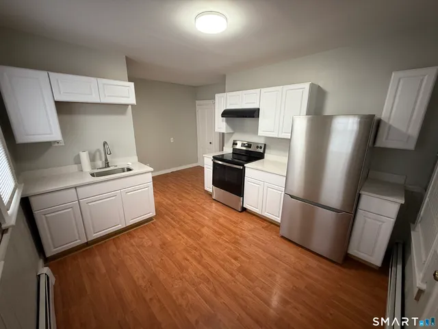 a kitchen with stainless steel appliances a refrigerator sink and wooden floor