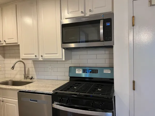 a kitchen with stainless steel appliances granite countertop white cabinets and black stove top oven with granite countertops