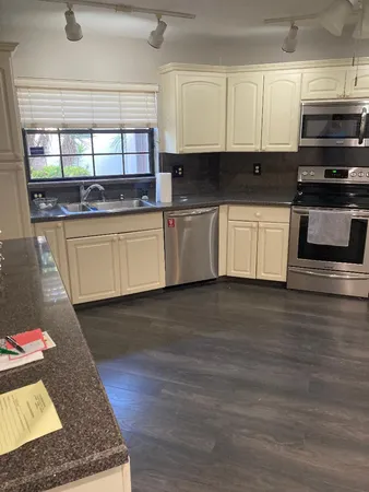 a kitchen with granite countertop wooden cabinets stainless steel appliances and a window