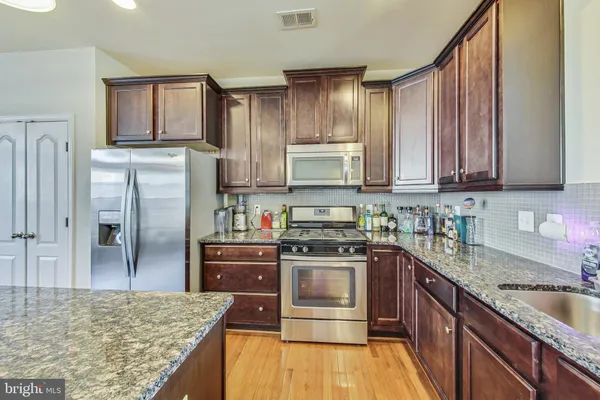 a kitchen with stainless steel appliances granite countertop a stove top oven a sink and dishwasher