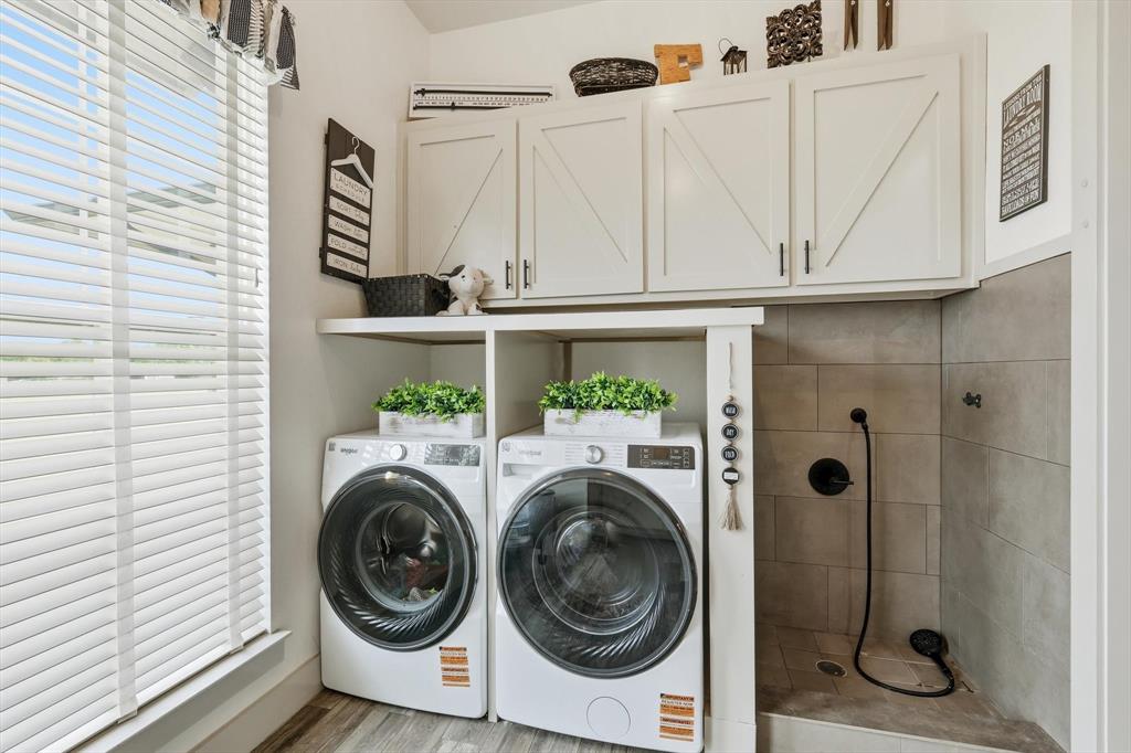 6020 Honeysuckle Road Midlothian, TX 76065 - Photo 15 of 39 Dedicated laundry area featuring a built-in pet washing station, upper white cabinetry with barn door accents, and wood-finish flooring