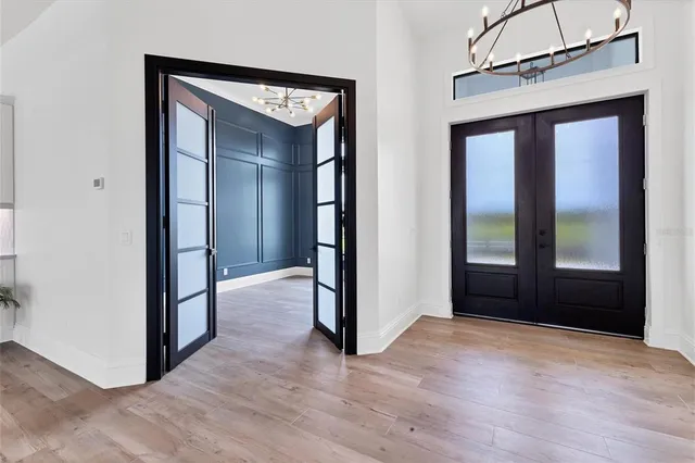 an empty room with wooden floor and a hallway