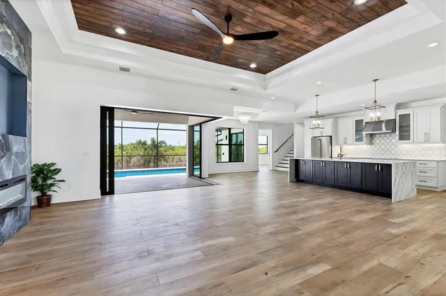 a view of an empty room with wooden floor and a kitchen