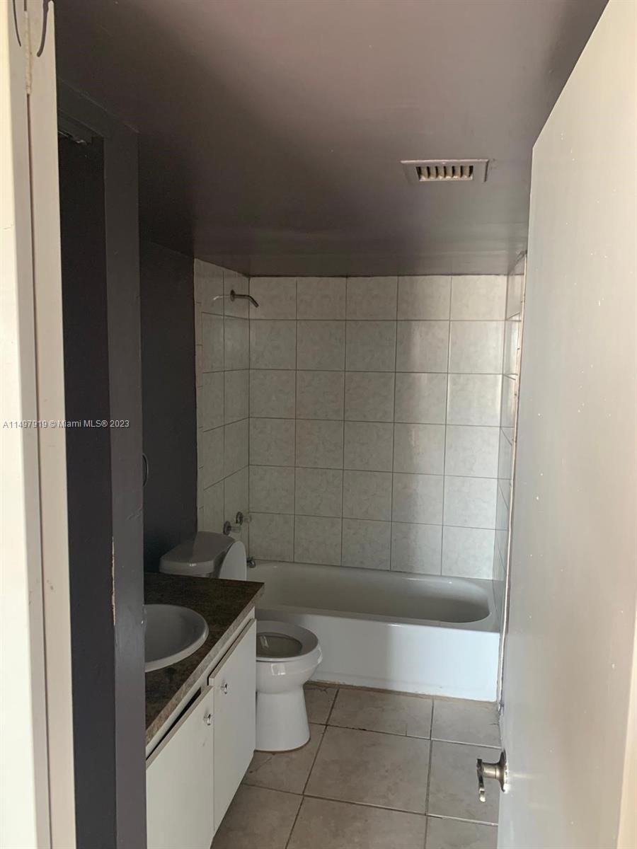 4174 Inverrary Drive, Unit 906 Lauderhill, FL 33319 - Photo 7 of 9 a bathroom with a granite countertop sink a toilet and bathtub