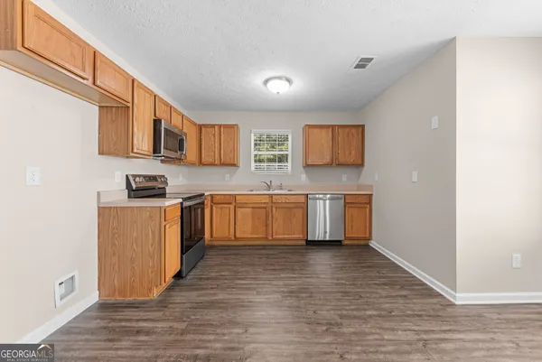 a kitchen with stainless steel appliances granite countertop a sink cabinets and wooden floor