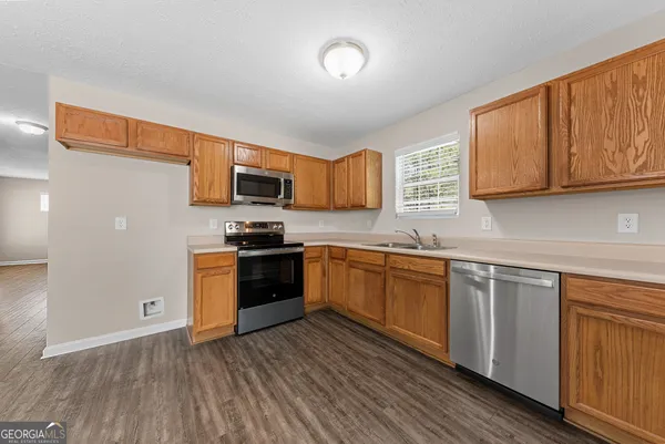 a kitchen with granite countertop wooden floors stainless steel appliances and sink