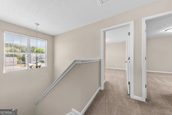 a view of hallway with window and wooden floor